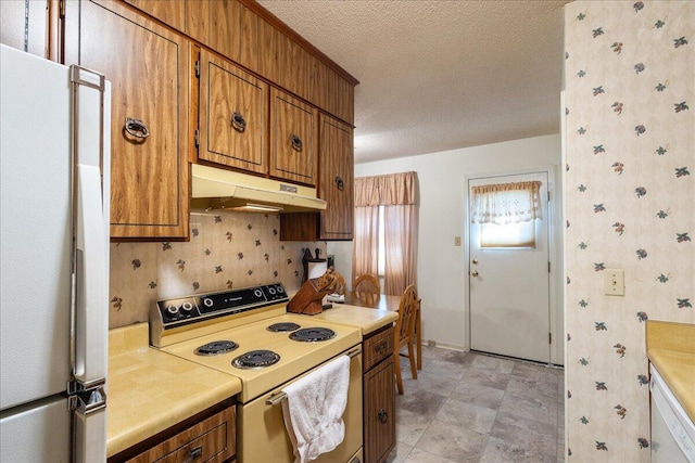 kitchen with tasteful backsplash, white appliances, and a textured ceiling