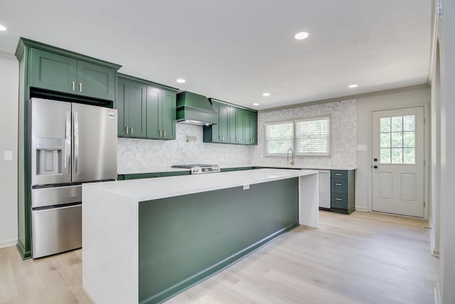 kitchen featuring green cabinetry, appliances with stainless steel finishes, custom exhaust hood, and light wood-style floors