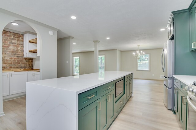 kitchen featuring stainless steel appliances, a center island, light wood-style flooring, and green cabinets
