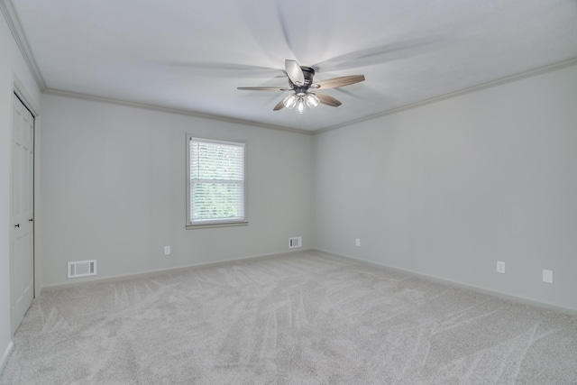 carpeted spare room featuring baseboards, ornamental molding, a ceiling fan, and visible vents