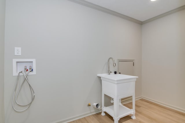 clothes washing area with laundry area, light wood finished floors, hookup for a washing machine, baseboards, and ornamental molding