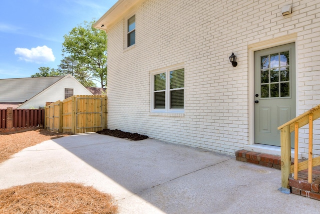 exterior space with fence, a gate, a patio, and brick siding