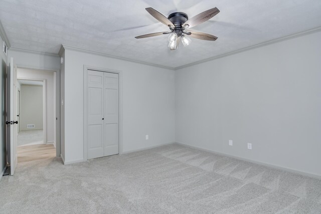 unfurnished bedroom featuring light colored carpet, crown molding, visible vents, and a closet