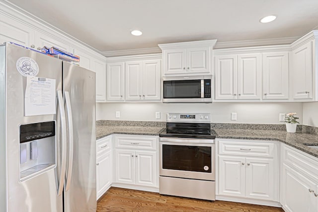 1009 Neilson St, Aiken, SC 29803 - kitchen with appliances with stainless steel finishes, white cabinetry, light wood-style flooring, dark stone countertops, and crown molding