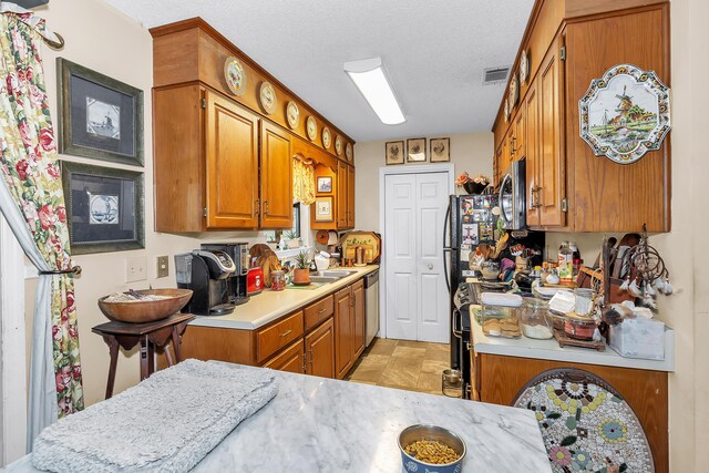 16 Cardinal Ln, North Augusta, SC 29841 - kitchen featuring appliances with stainless steel finishes, brown cabinets, light countertops, a textured ceiling, and a sink