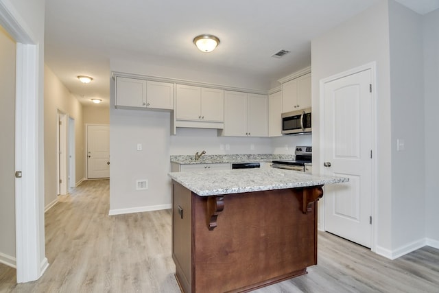 344 Bordeaux Dr, Thomson, GA 30824 - kitchen featuring sink, a center island, appliances with stainless steel finishes, light stone countertops, and light hardwood / wood-style floors