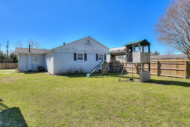 back of house featuring fence, cooling unit, a yard, a playground, and brick siding