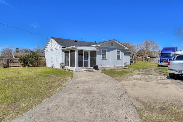 view of front facade featuring a shingled roof, a front yard, fence, and a sunroom