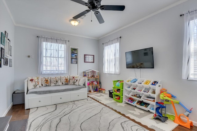 game room featuring a ceiling fan, crown molding, baseboards, and wood finished floors