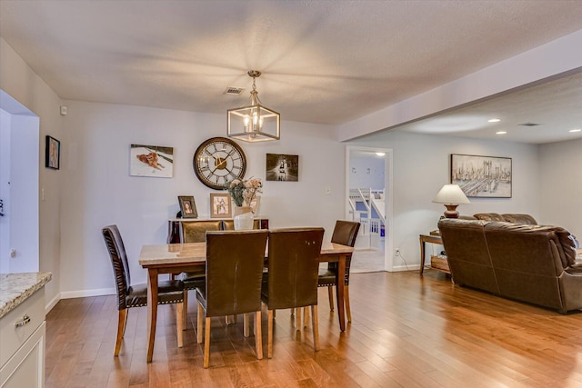 dining area with light wood-type flooring, an inviting chandelier, baseboards, and visible vents