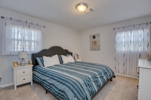 bedroom with baseboards, multiple windows, visible vents, and light colored carpet