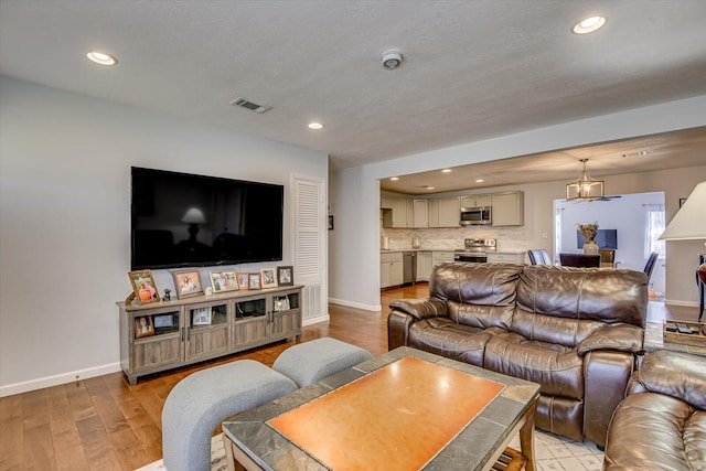 living room with light wood-style floors, recessed lighting, visible vents, and baseboards