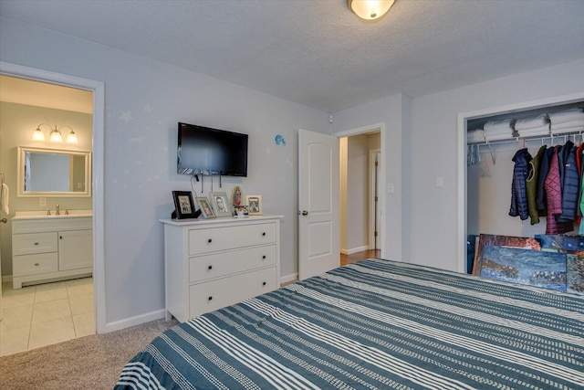 bedroom with light carpet, baseboards, a sink, a textured ceiling, and a closet