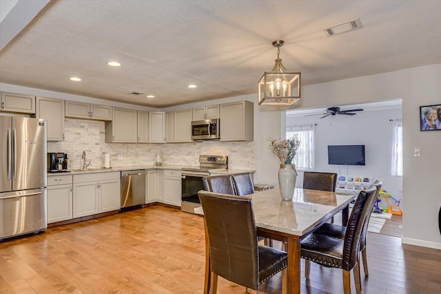 dining room with light wood-style flooring, ceiling fan with notable chandelier, visible vents, and recessed lighting