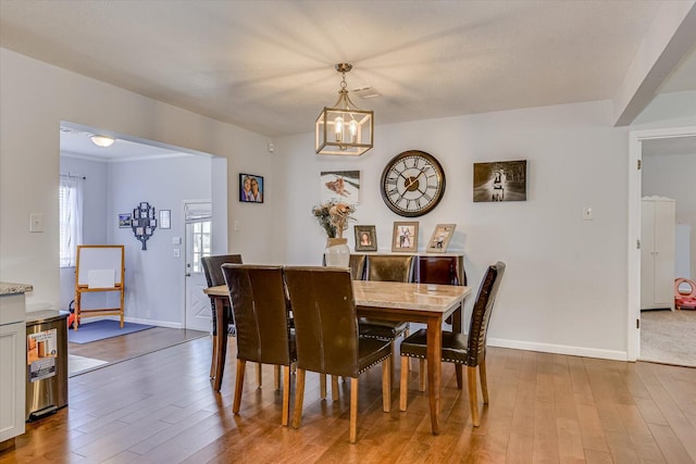 dining room featuring baseboards, wood finished floors, and an inviting chandelier