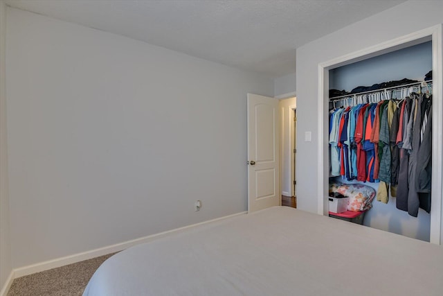 bedroom featuring carpet floors, a closet, a textured ceiling, and baseboards