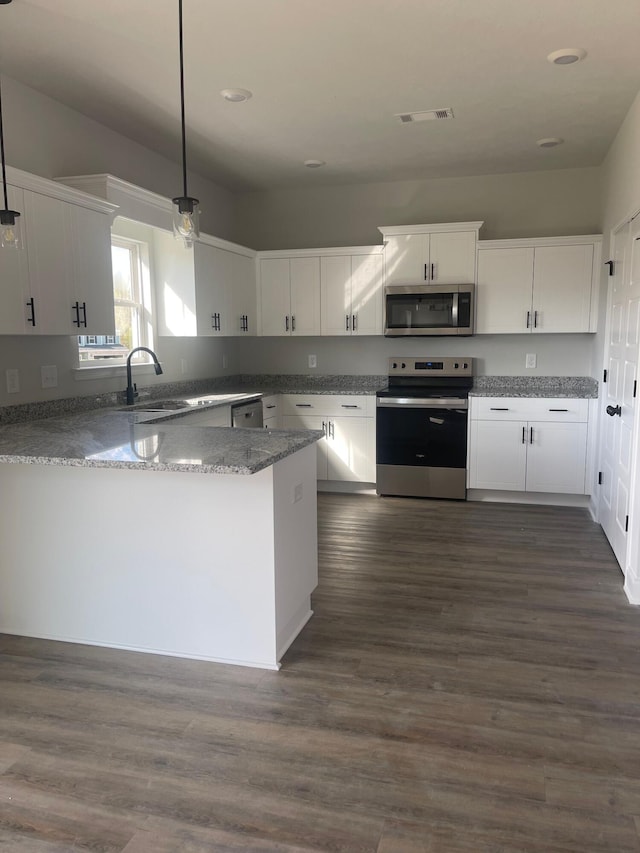 kitchen with white cabinets, sink, appliances with stainless steel finishes, decorative light fixtures, and kitchen peninsula