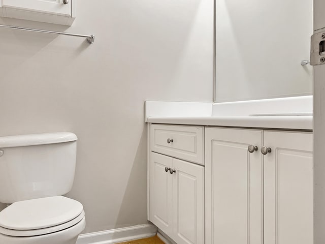 half bathroom with toilet, vanity, and baseboards