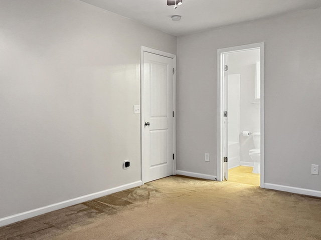 unfurnished bedroom with baseboards, carpet flooring, and connected bathroom