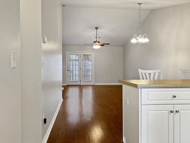 kitchen featuring dark wood-style flooring, white cabinets, baseboards, lofted ceiling, and ceiling fan with notable chandelier
