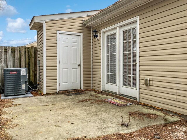 property entrance with central AC unit, fence, and a patio