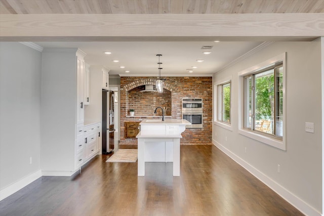 118 Lake Bluff Dr, Waynesboro, GA 30830 - kitchen featuring stainless steel appliances, light countertops, an island with sink, white cabinetry, and brick wall