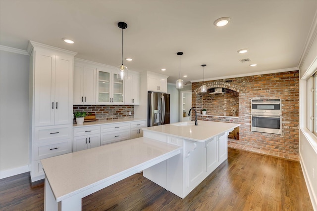 118 Lake Bluff Dr, Waynesboro, GA 30830 - kitchen featuring stainless steel appliances, a large island with sink, light countertops, white cabinets, and brick wall