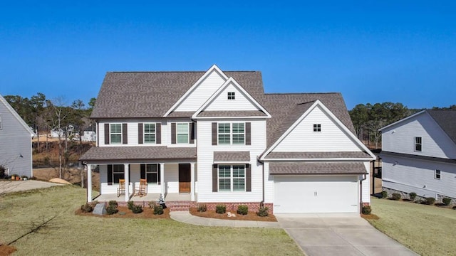 view of front of house featuring roof with shingles, covered porch, a front yard, a garage, and driveway