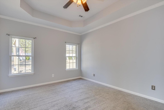 carpeted spare room with a raised ceiling, ornamental molding, and ceiling fan