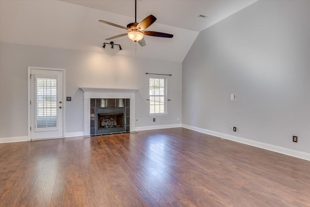 unfurnished living room with a tiled fireplace, ceiling fan, vaulted ceiling, and a healthy amount of sunlight