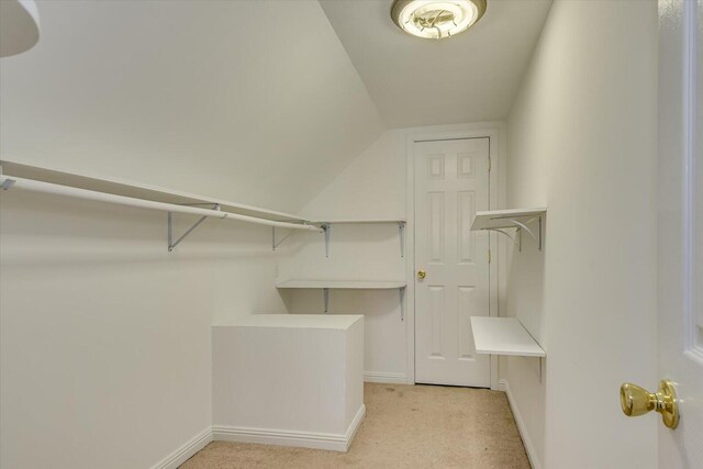 walk in closet with lofted ceiling and light colored carpet