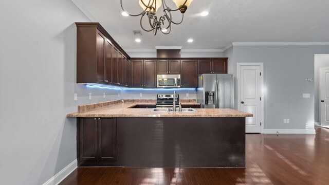 kitchen featuring decorative light fixtures, ornamental molding, a notable chandelier, dark brown cabinetry, and stainless steel appliances