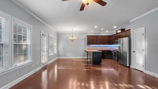 kitchen featuring sink, stainless steel appliances, hanging light fixtures, a kitchen island, and ornamental molding