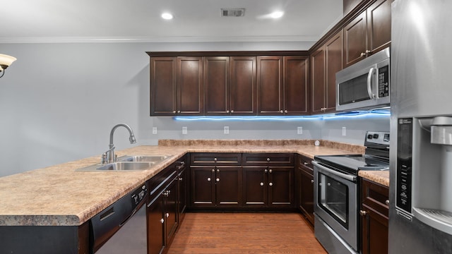 kitchen with kitchen peninsula, stainless steel appliances, crown molding, sink, and hardwood / wood-style floors