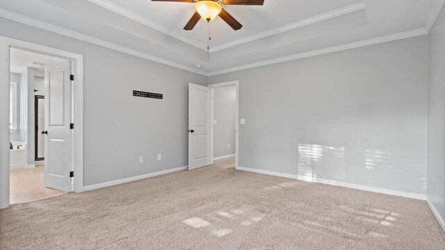 spare room with a raised ceiling, light carpet, crown molding, and ceiling fan