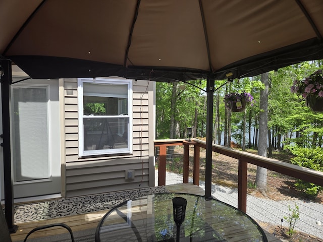 wooden deck featuring outdoor dining space and a gazebo