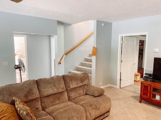 living room with baseboards, light carpet, stairs, and a textured ceiling