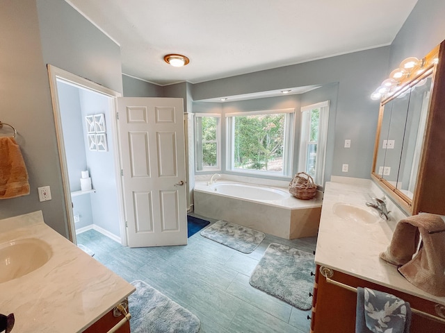 bathroom with two vanities, a garden tub, and a sink