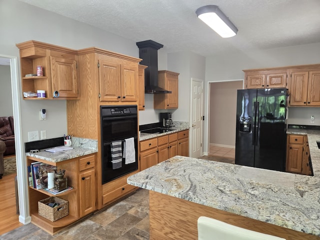 kitchen with black appliances, open shelves, wall chimney range hood, and light stone counters