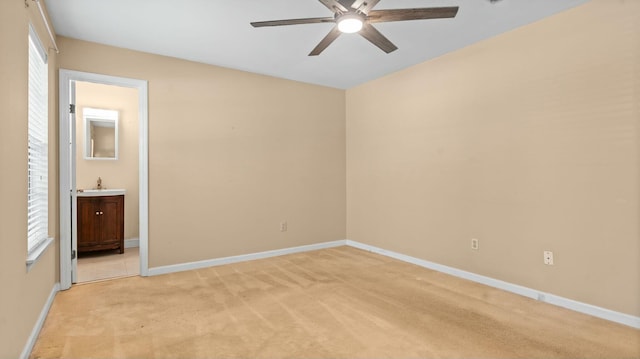unfurnished bedroom with baseboards, connected bathroom, ceiling fan, and light carpet