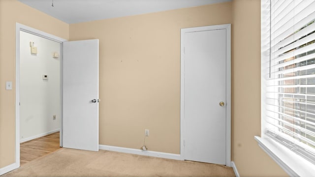 unfurnished bedroom with baseboards, multiple windows, and carpet floors