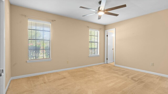 carpeted spare room with ceiling fan and baseboards