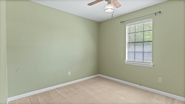 spare room featuring light colored carpet, baseboards, and a ceiling fan