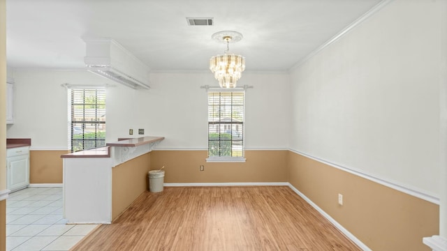 unfurnished dining area featuring crown molding, visible vents, baseboards, and an inviting chandelier