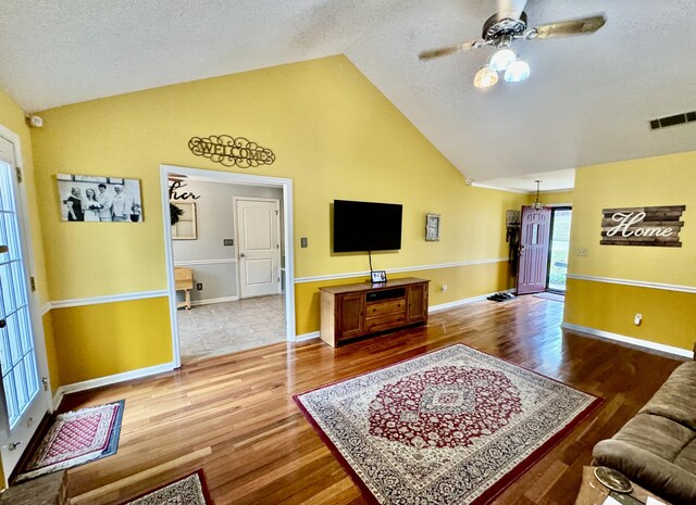 living room featuring a textured ceiling, ceiling fan, hardwood / wood-style floors, and lofted ceiling