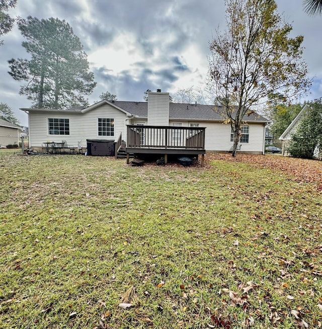 back of property featuring a yard, a wooden deck, and a hot tub