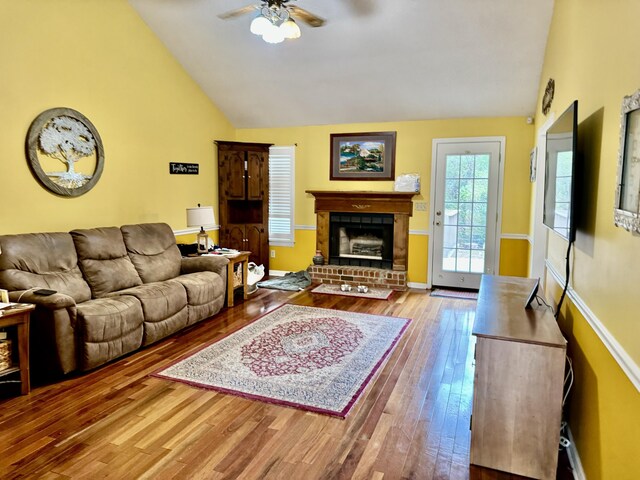 living room featuring a fireplace, light hardwood / wood-style floors, high vaulted ceiling, and ceiling fan