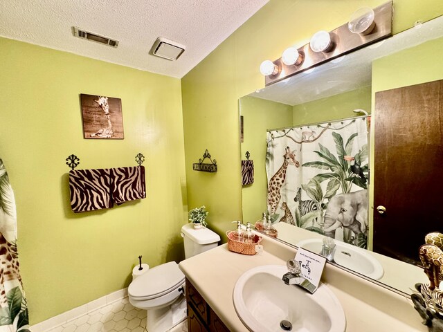 bathroom with tile patterned floors, vanity, a textured ceiling, and toilet