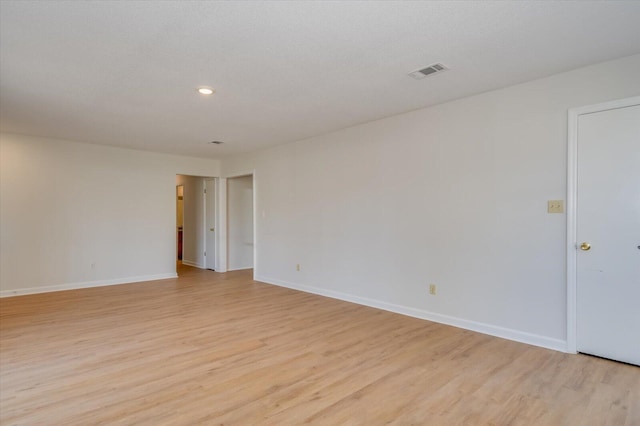 spare room featuring light wood-type flooring, visible vents, baseboards, and recessed lighting