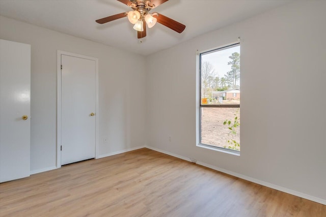 spare room featuring baseboards, a ceiling fan, a wealth of natural light, and light wood-style floors